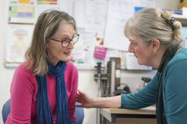 A concerned GP comforts a woman with ovarian cancer in the GP's office