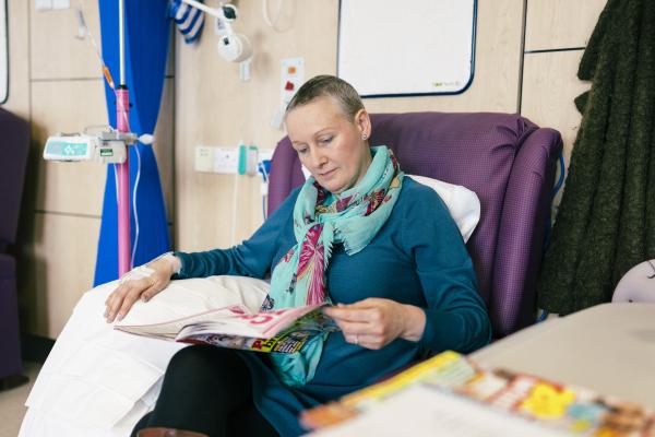A woman reading a magazine while having chemotherapy