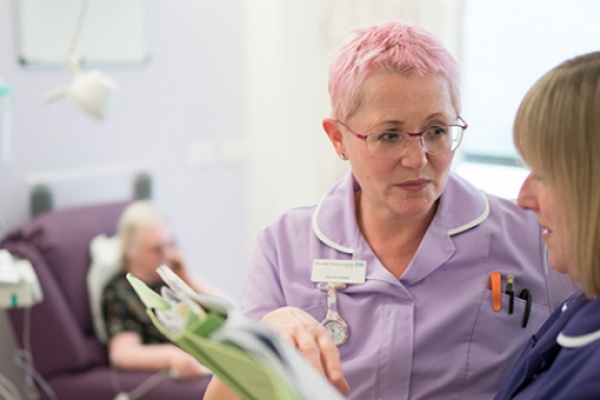 Two nurses discuss patient notes in a chemotherapy unit