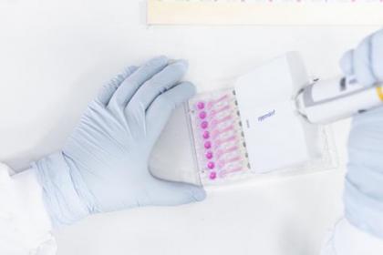 A closeup of a researcher wearing gloves while using lab equipment