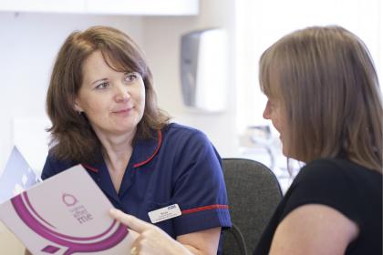 A nurse talking through a Target Ovarian Cancer leaflet with a woman