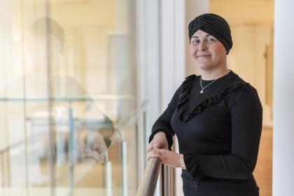 A woman with ovarian cancer smiling wearing a black head scarf and a black top