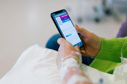 Close up of a woman looking at Target Ovarian Cancer's website on her phone during chemotherapy