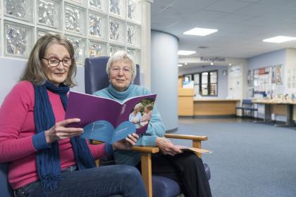 Two women reading a Target Ovarian Cancer guide in a hospital