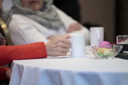 Close up of a cup of tea with two women talking in the background at a Target Ovarian Cancer support event