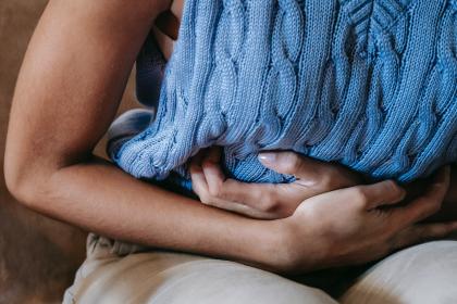 Close up of a woman with her hands on her bloated tummy