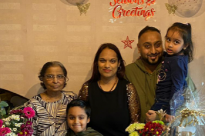 Lena with her mum Savita at a 40th birthday party surrounded by their family, a cake, flowers and some cards