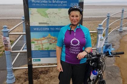A target ovarian cancer fundraiser smiling next to her bike at the seafront