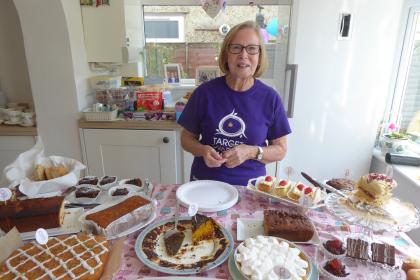 Pauline, a Target Ovarian Cancer fundraiser, standing behind a table of homemade cakes