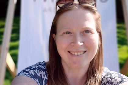 Claire smiling with a deckchair behind her