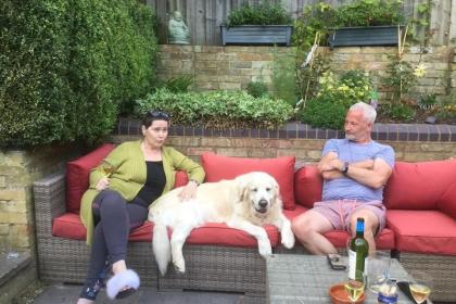 Lorraine sitting on a sofa outside next to a dog enjoying time with friends