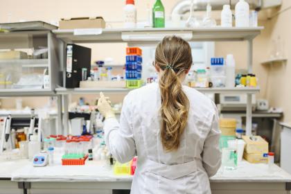 A female researcher facing away from the camera using equipment in a lab