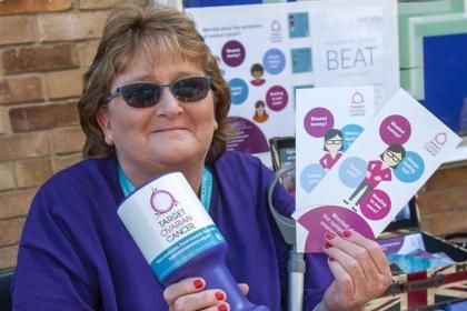 Diane out fundraising in her local community, holding a collection tin and Target Ovarian Cancer posters and leaflets