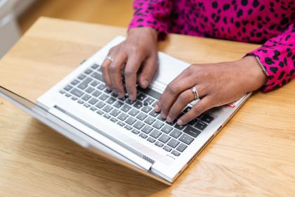 A person's hands typing on a laptop