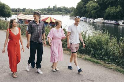 Four people walking along river