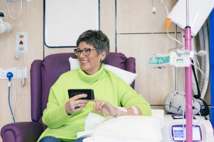 Woman holding her phone and smiling in hospital