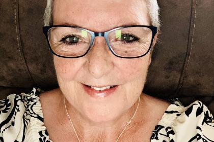 A selfie of Dot with short blonde hair wearing glasses and smiling
