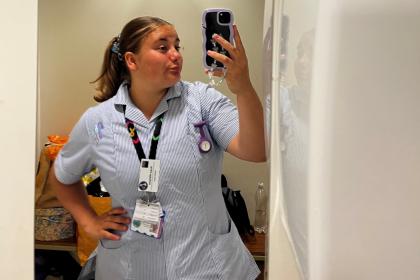 Rosie taking a photo in the mirror wearing her student nurse uniform