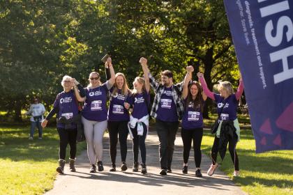 A group of fundraisers in Target Ovarian Cancer t-shirts, walking with their arms in the air