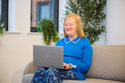 Woman sitting on sofa looking at laptop on her lap