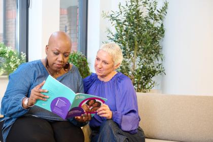 Two women sitting together reading a guide