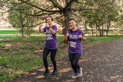 Two female supporters smiling and running at the Target Ovarian Cancer's London Walk|Run event 2023