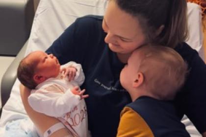 Grace holding her child and newborn baby.