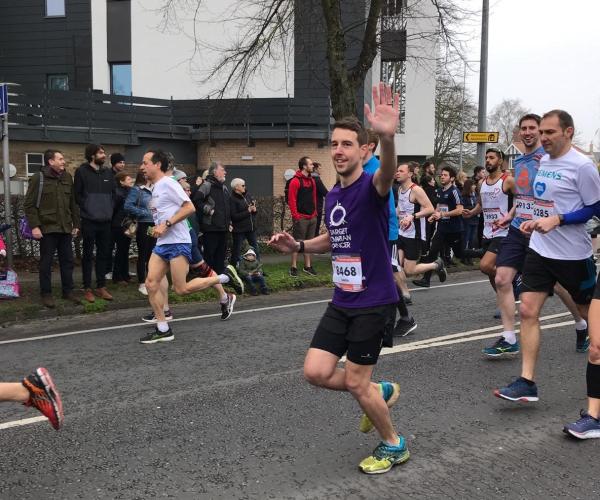 Target Ovarian Cancer fundraiser running and waving during a 10K