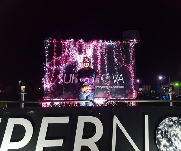 Target Ovarian Cancer fundriaser standing on a lit up podeum at night - Mary - Kelpies Supernova 5k