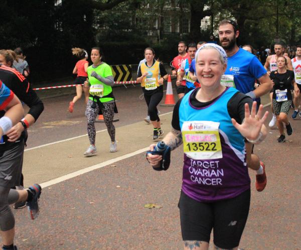 A Target Ovarian Cancer fundraiser at the Royal Parks Half Marathon running and waving