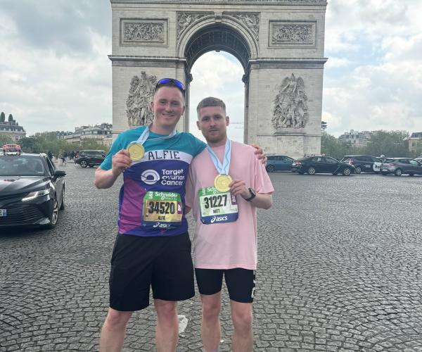 Two male supporters smiling with medals at the Paris Marathon 2025
