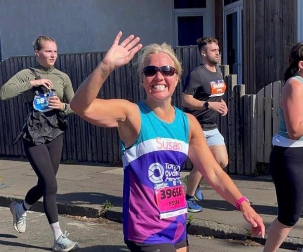 Female supporter smiling and running at Edinburgh Half Marathon 2025