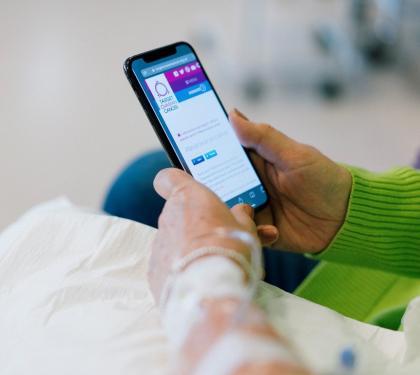 Close up of a woman looking at Target Ovarian Cancer's website on her phone during chemotherapy