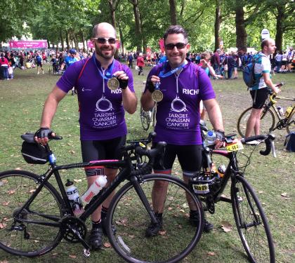 Two Target Ovarian Cancer cyclists at the end of their fundraising event holding their bikes and medals