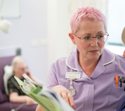 Two nurses discuss patient notes in a chemotherapy unit