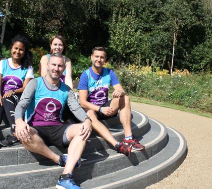 A group of Target Ovarian Cancer runners sat by a statue smiling in the sunshine