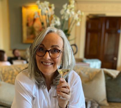 Helen wearing glasses and holding a glass of wine