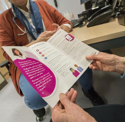 Close up of a woman holding an open Target Ovarian Cancer information leaflet