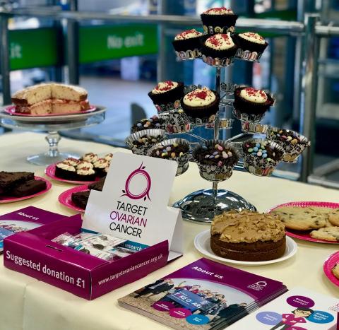 Target Ovarian Cancer bake sale with cupcakes, layer cakes and charity pin badges and leaflets on a table