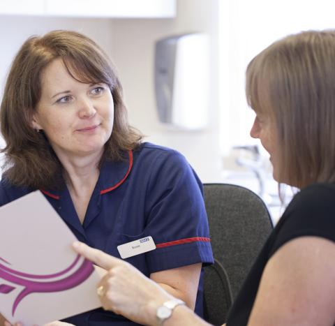 A nurse talking through a Target Ovarian Cancer leaflet with a woman