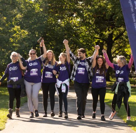 A group of fundraisers in Target Ovarian Cancer t-shirts, walking with their arms in the air