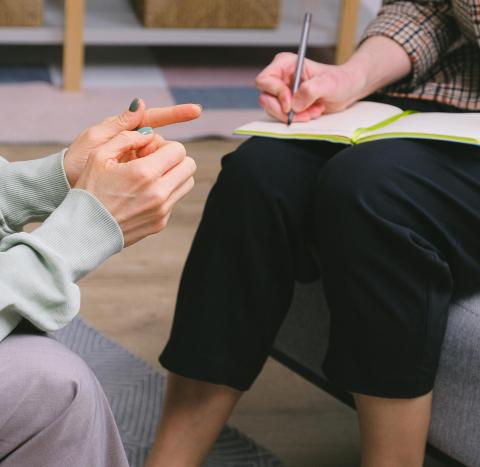 Doctor writing in notebook, whilst patient speaks