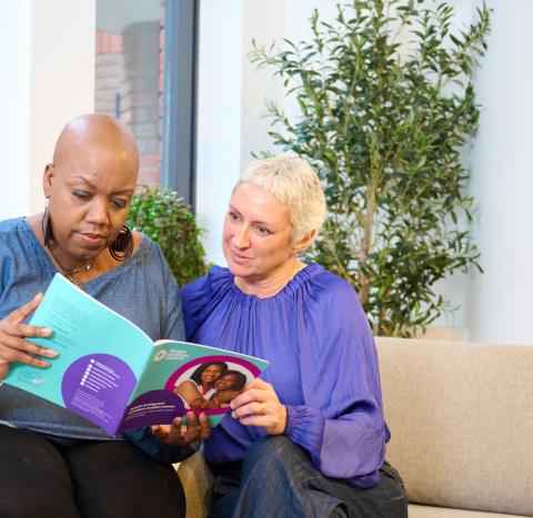 Two women sitting together reading a guide