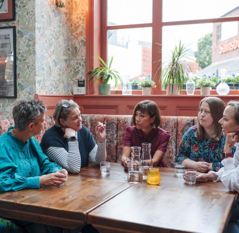 Group of women sat around a table talking