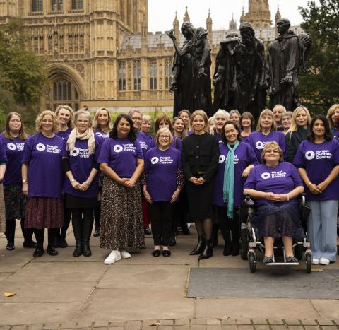 A group of Target Ovarian Cancer campaigners standing outside parliament wearing purple TOC tshirts with new CEO Catherine standing in the middle