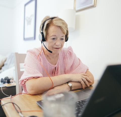 Woman wearing headset using laptop