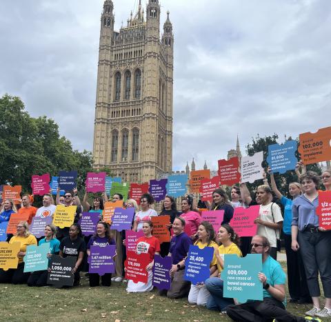 Campaigners pose with brightly coloured placards in front of the Palace of Westminster.