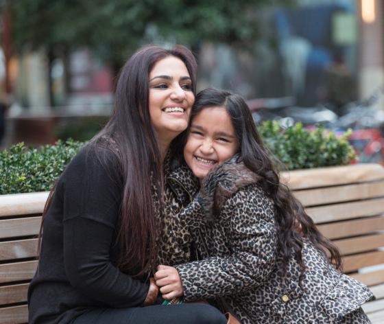 mother and daughter embracing on a bench