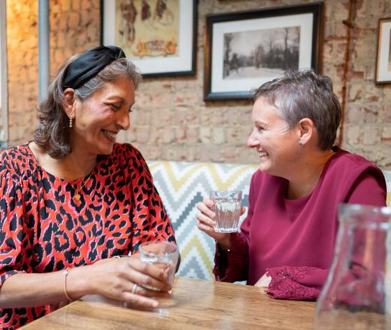 Two women laughing and talking in a restaurant
