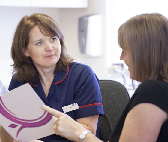 A nurse talking through a Target Ovarian Cancer leaflet with a woman